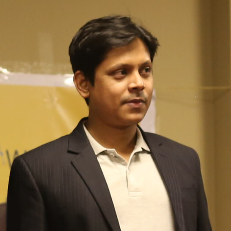 A suited man poses in front of a banner, showcasing his role as Digital Marketing Manager Abdullah Allamin Rankupper.