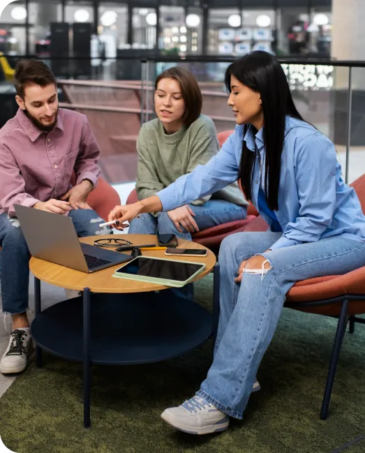 A group of three individuals engaged in discussion at a table with a laptop, displayed on the Rankupper home page.